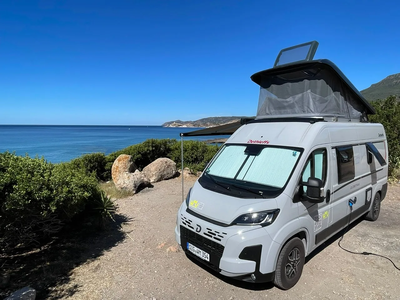 Frontansicht des Dethleffs Globetrail mit Sonnenschutz und Aufstelldach am Meer