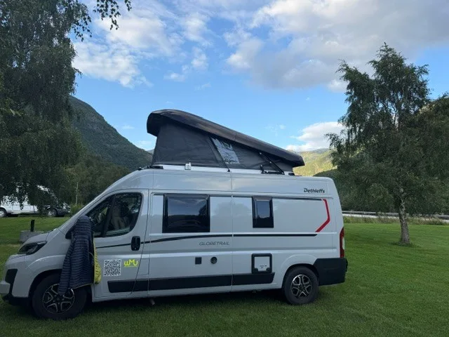 Dethleffs Globetrail mit aufgestelltem Dach auf einer Wiese vor Bergkulisse
